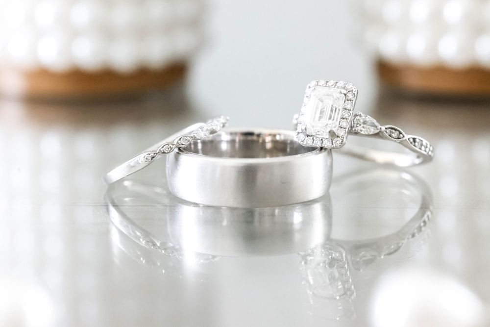 Elegant diamond engagement ring and wedding band set on reflective surface.
