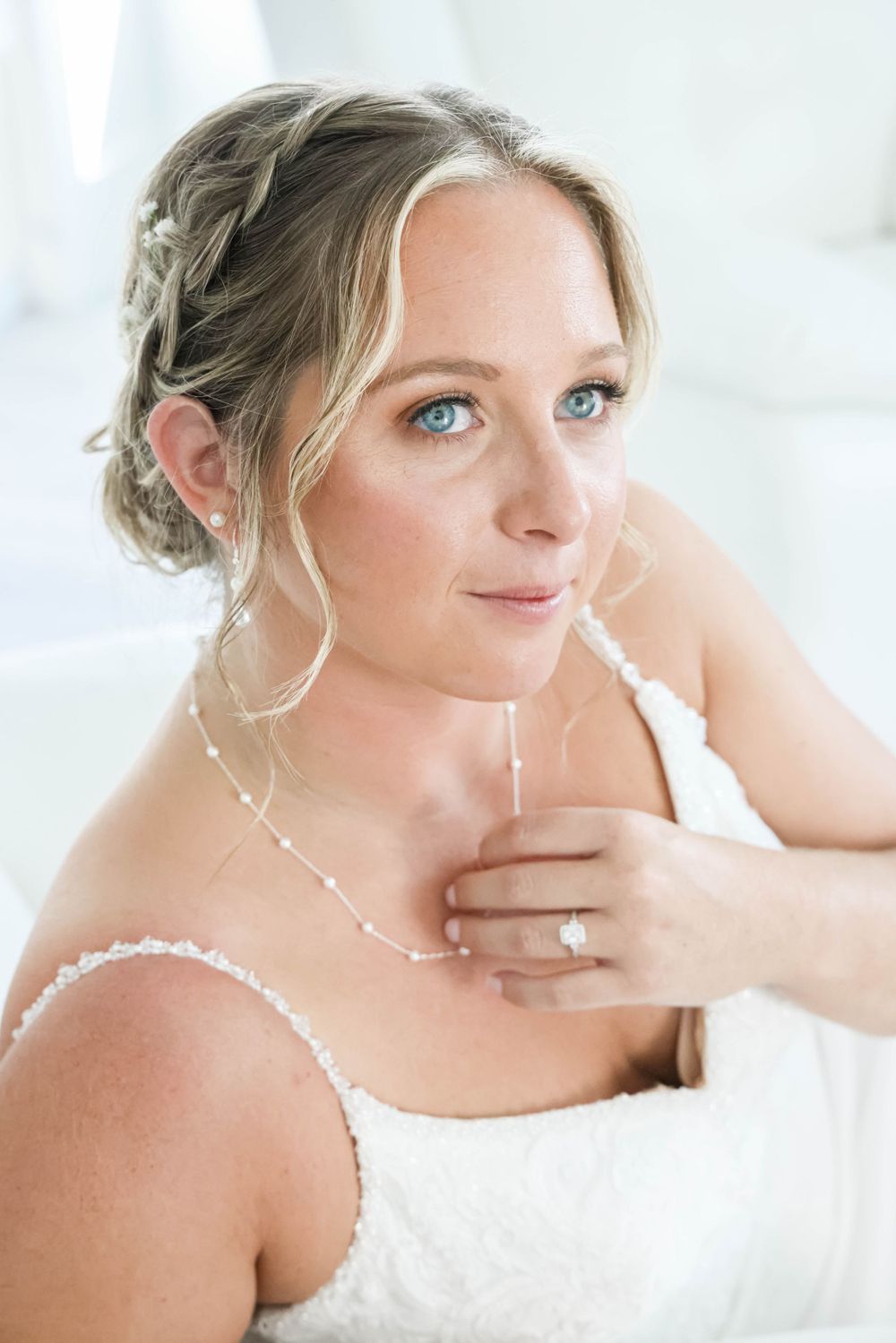A bridal portrait showing delicate lace details, braided updo, and subtle jewelry.