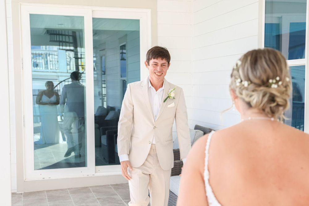 A first look moment between couple on a bright porch with glass windows.