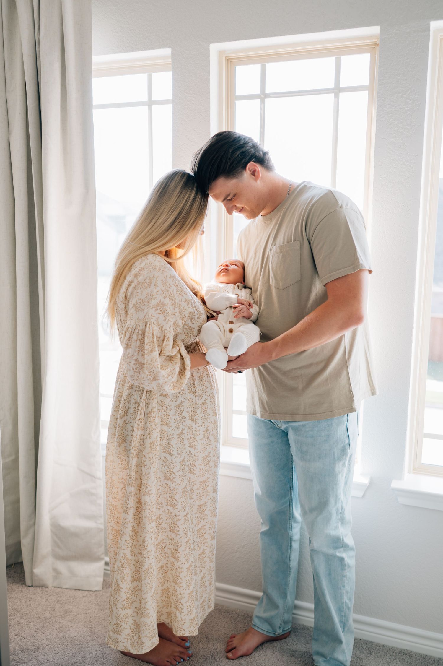Tender moment between new parents holding their newborn in a bright nursery.