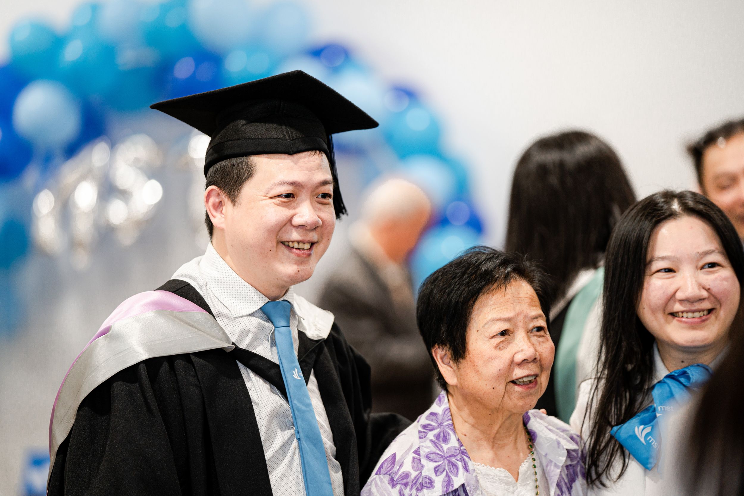 Graduation celebration with blue balloon decor and academic regalia.