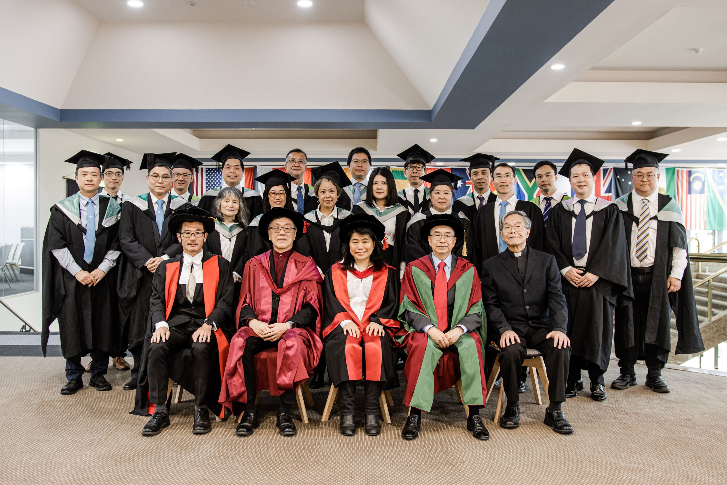 Group photo of graduates in black caps and gowns with red academic stoles.