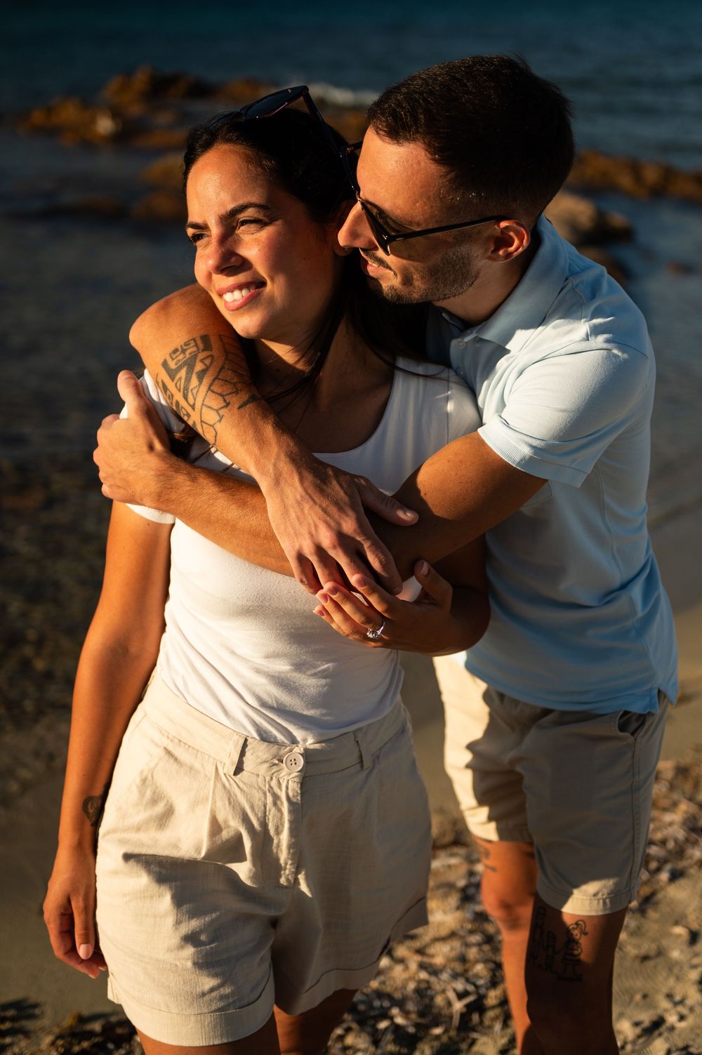 Intimate beach photoshoot with couple in casual white outfits at golden hour.