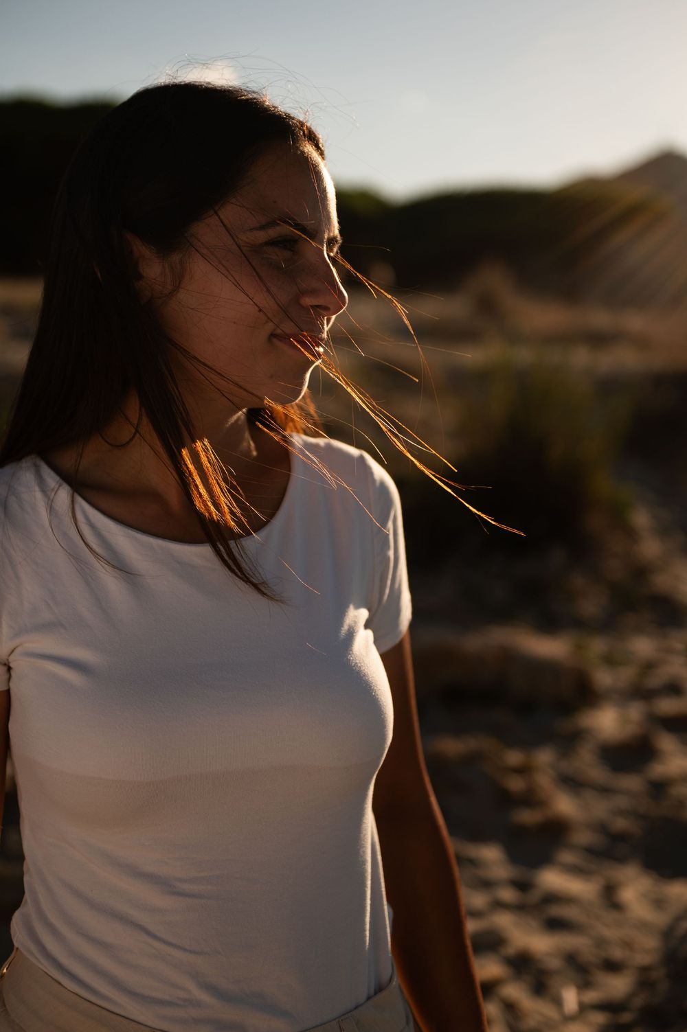 Profile portraits at sunset showing hair blowing in wind against natural backdrop.