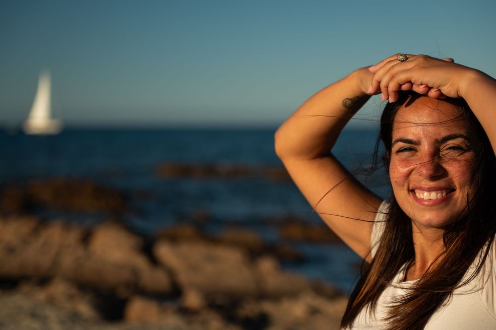Close-up portrait at sunset with golden light creating a dreamy beach atmosphere.