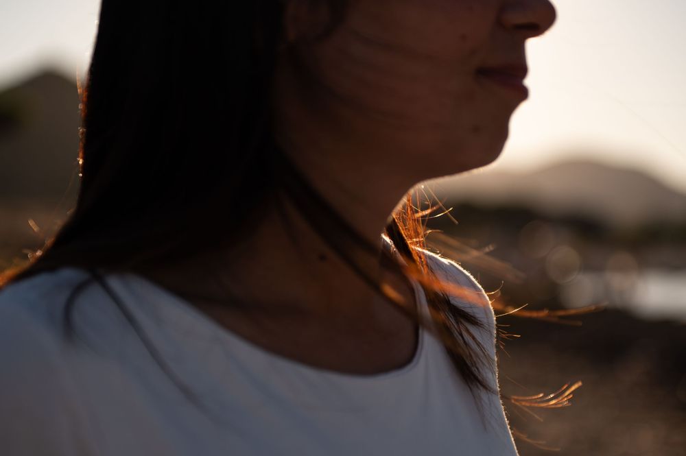 Side profile portraits with soft sunset lighting and coastal scenery.