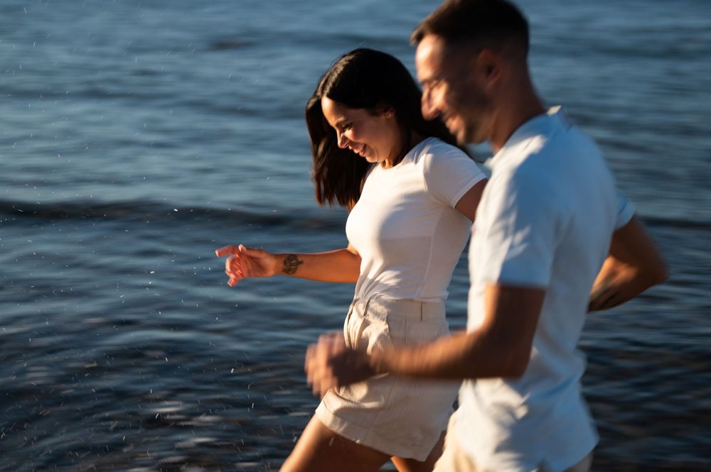Couple walking along the shoreline during sunset.