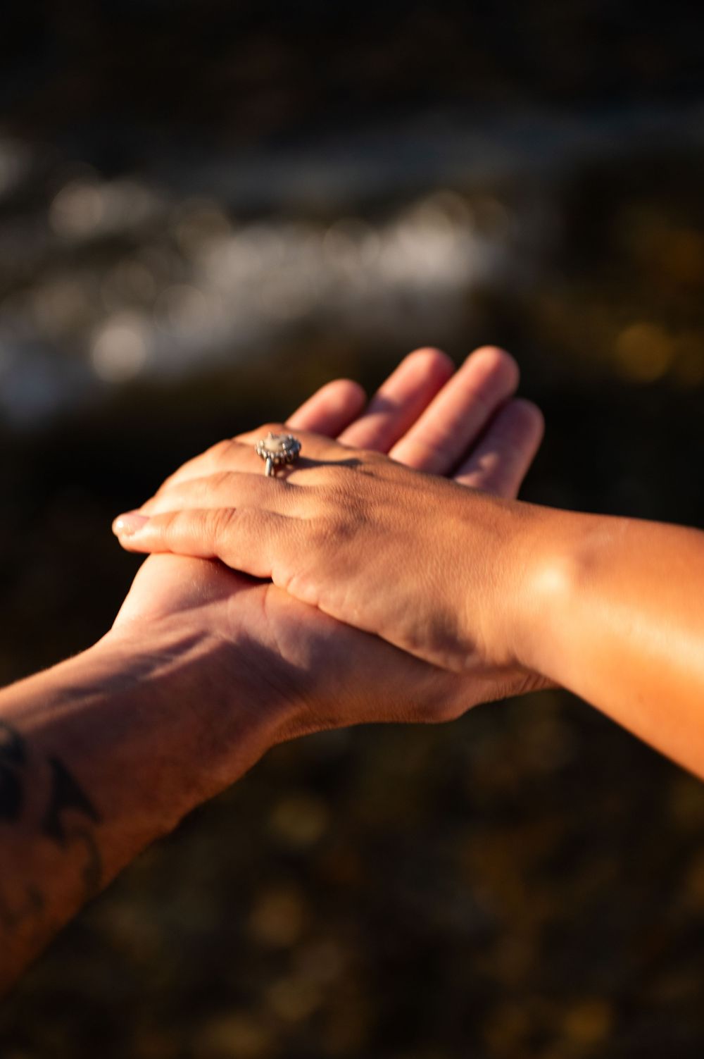 Close-up sequence of hands joining together against dark background in romantic gesture.