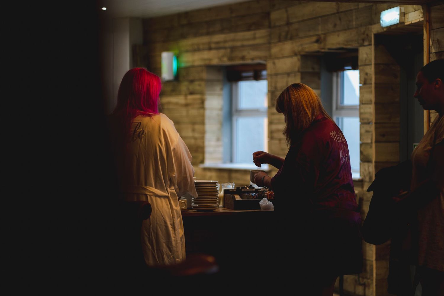 Two figures in dim lighting having coffee at a rustic cafe with stone walls.