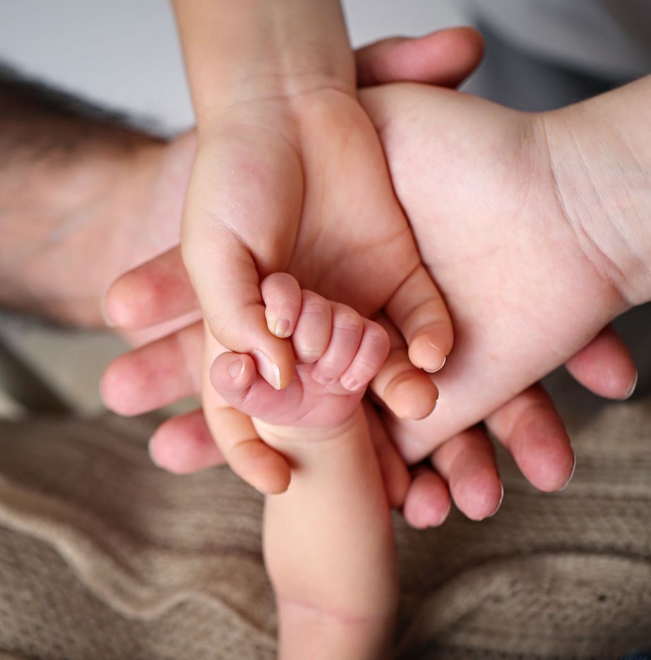 Close-up of adult hands gently cradling tiny baby feet.