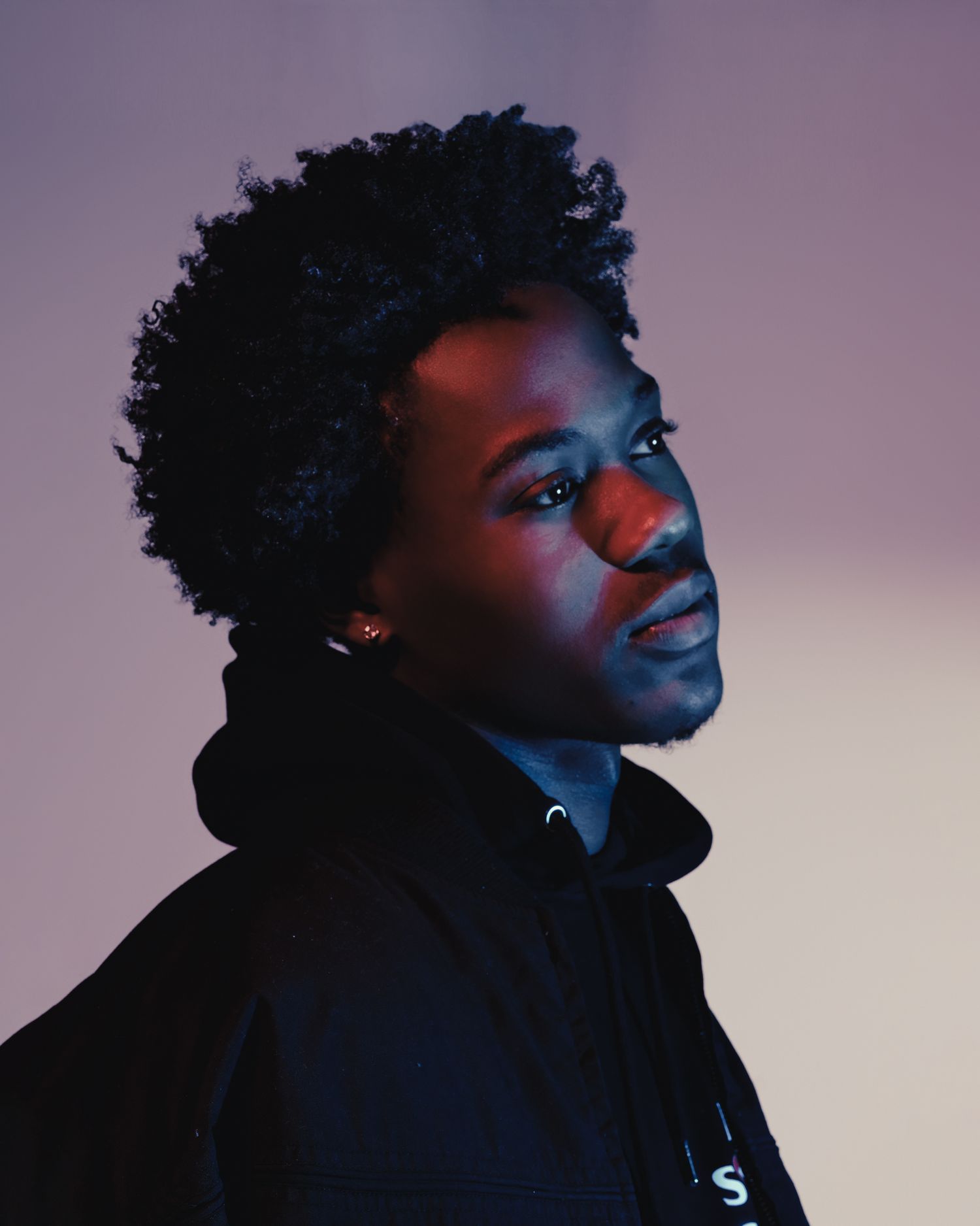 Artistic portrait with natural hair illuminated by red and blue lighting effects.