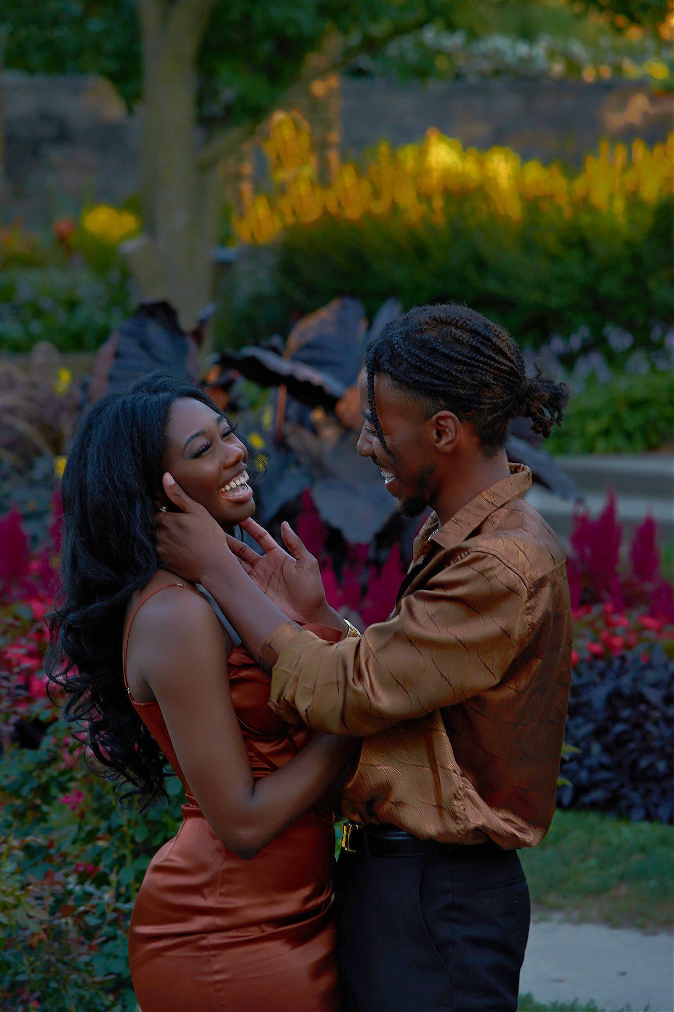 Romantic evening portrait in garden with golden lighting and red flowers.