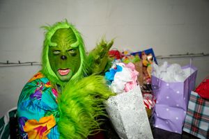 Person wearing bright green Grinch costume interacting with party guests.