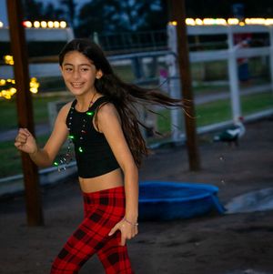 Person in red plaid outfit dancing outdoors at dusk.