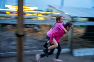 Motion blur of people running and jumping in an outdoor playground area.