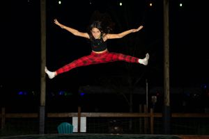 Person performing gymnastic splits jumps in a dark indoor space.