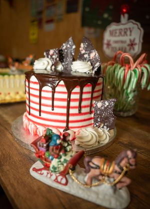 Festive holiday cake decorated with candy canes, chocolate drip, and Christmas ornaments.