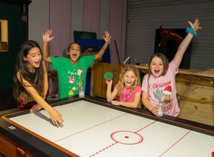 Kids playing an interactive game on a white surface with excited expressions.