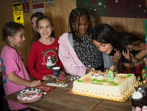 Kids gathered around birthday cakes at holiday themed celebration party.