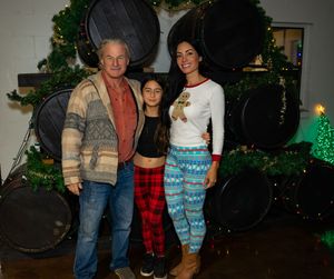 Group of people gathered together at a festive holiday party with Christmas decorations in the background.
