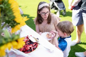 Children playing outdoor party games with colorful decorations and activities in a sunny garden setting.