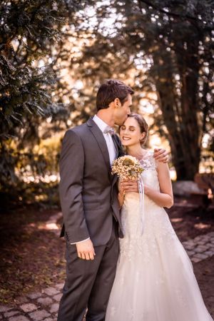 Warm sunset wedding portrait in garden setting with couple in elegant attire.