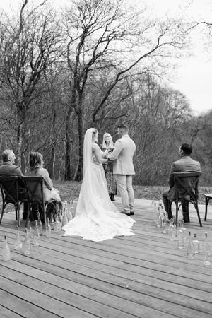 Black and white photo series showing a wedding ceremony progression on a wooden deck surrounded by bare trees.