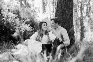 Black and white romantic couple engagement photos captured in a dreamy forest setting with sunlight filtering through trees.