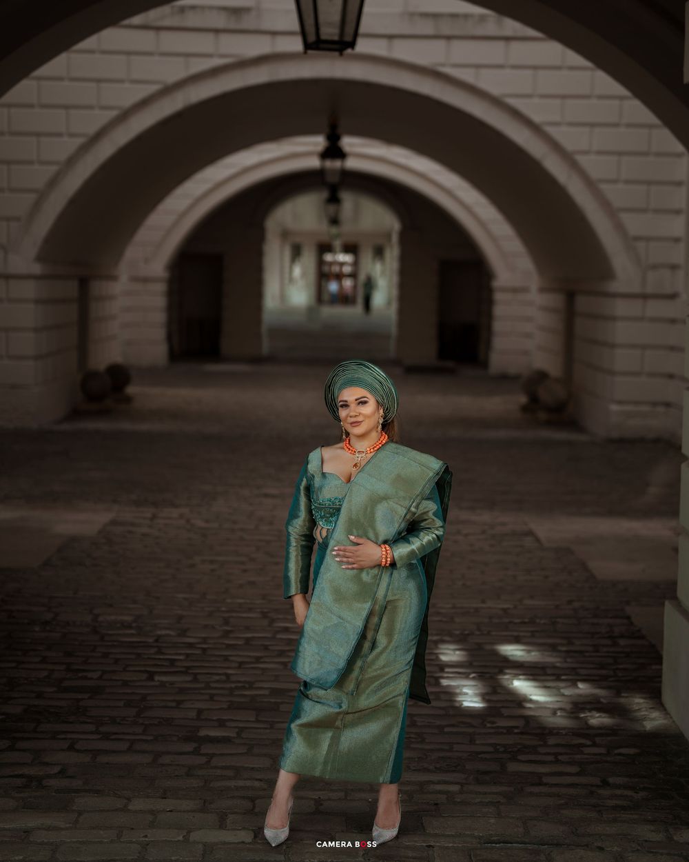Fashion portrait session in a historic courtyard with arched columns and cobblestone flooring.