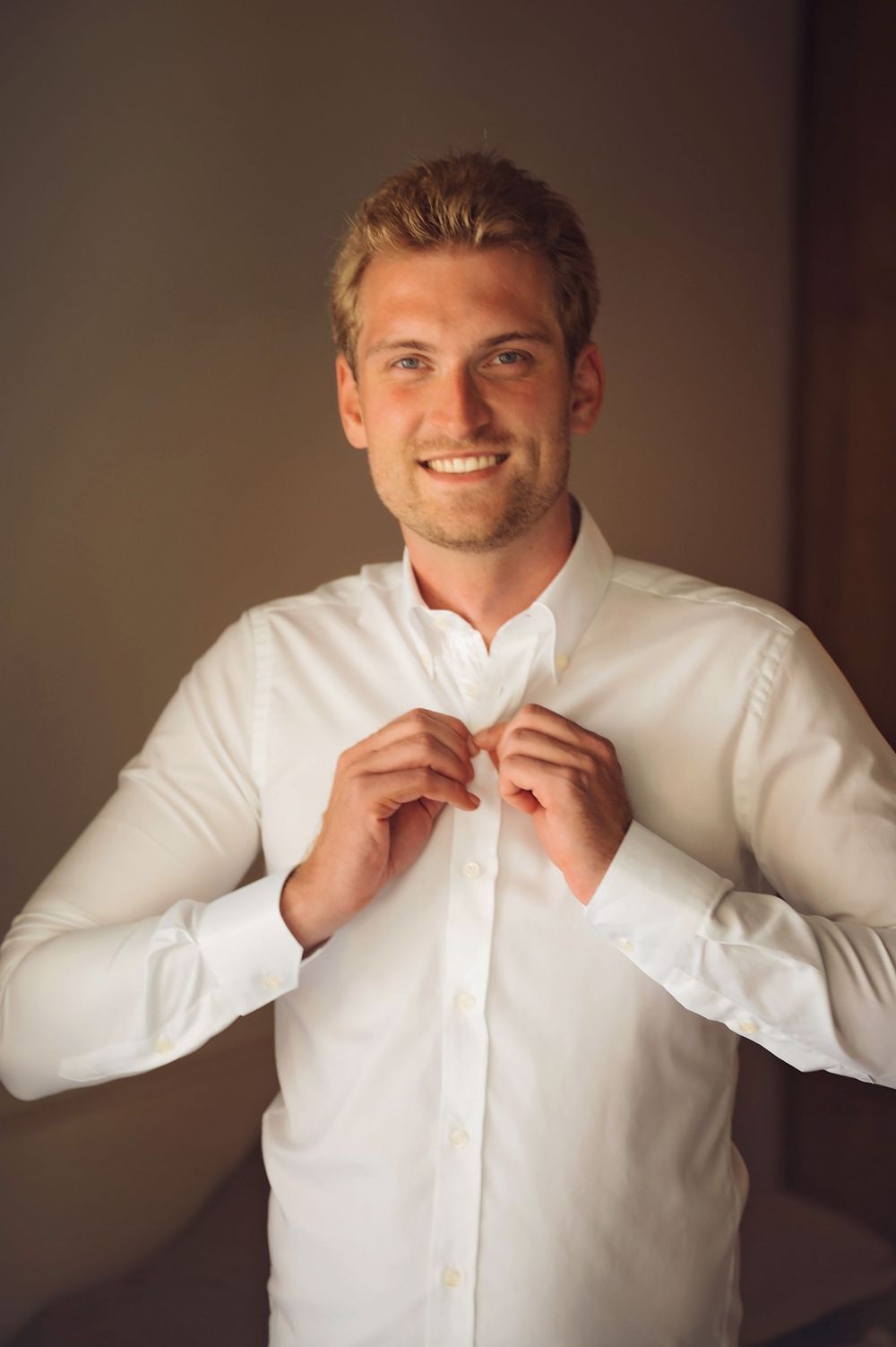 Getting dressed in a crisp white button-down shirt while adjusting the collar in sequence.