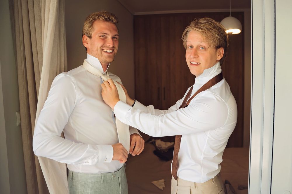 Wedding party members embracing and celebrating in formal white attire.