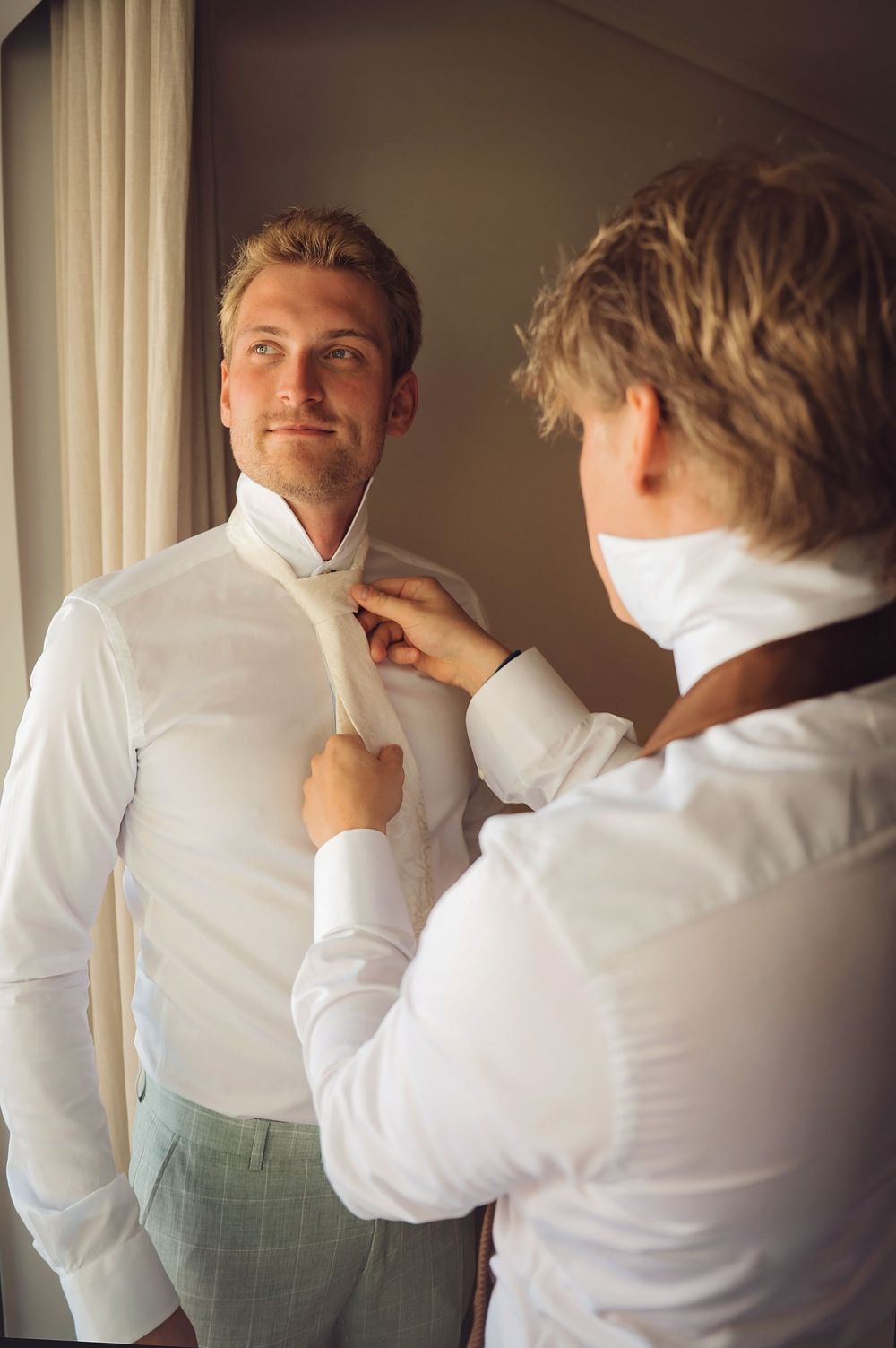 Getting ready sequence showing wedding day preparations in white dress shirts.