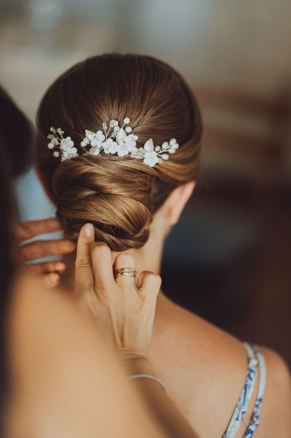 Delicate pearl and crystal hair accessories being placed in an elegant bridal updo.