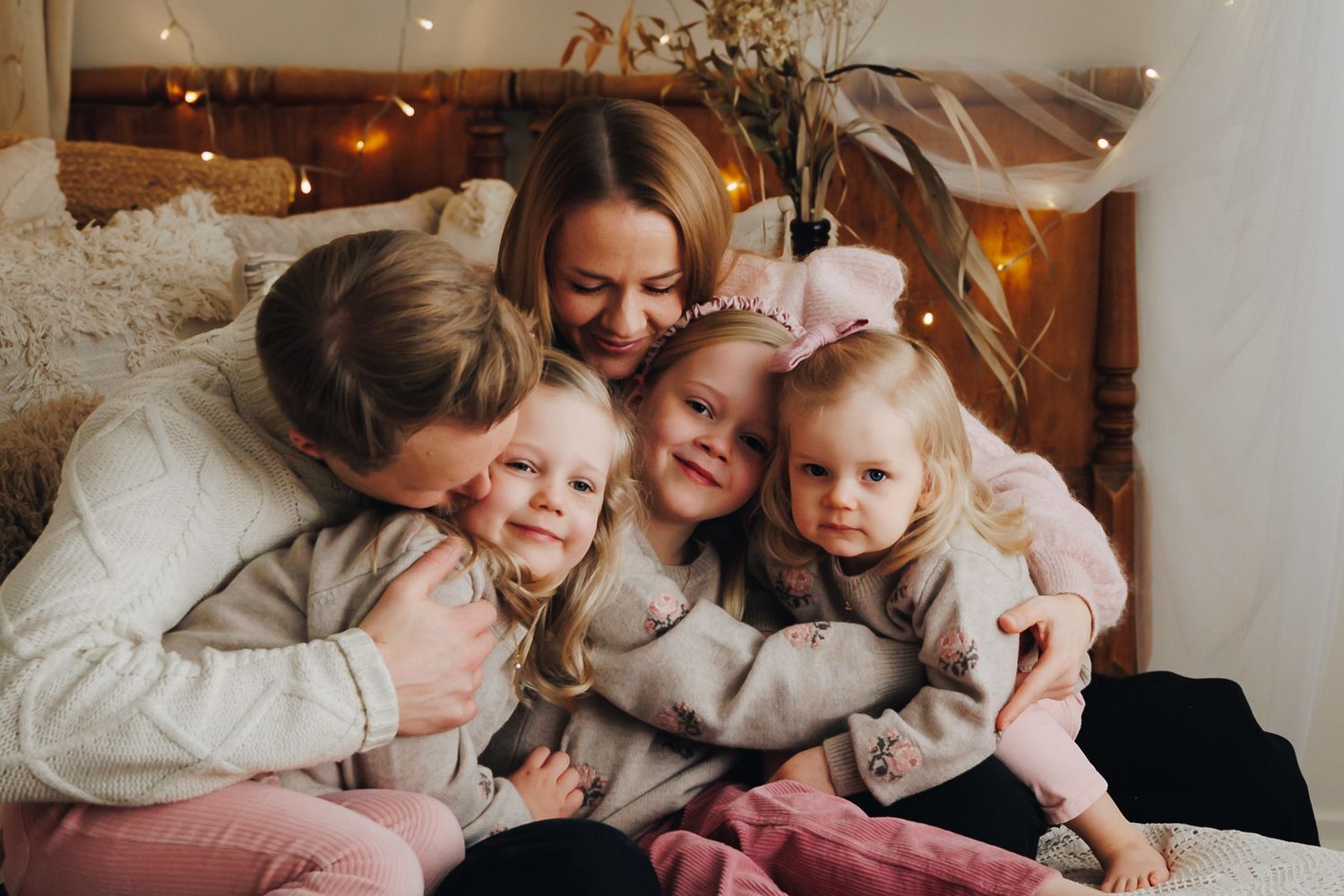 A family gathers on a couch sharing warm smiles and embraces in natural lighting mixed with cozy indoor ambiance.
