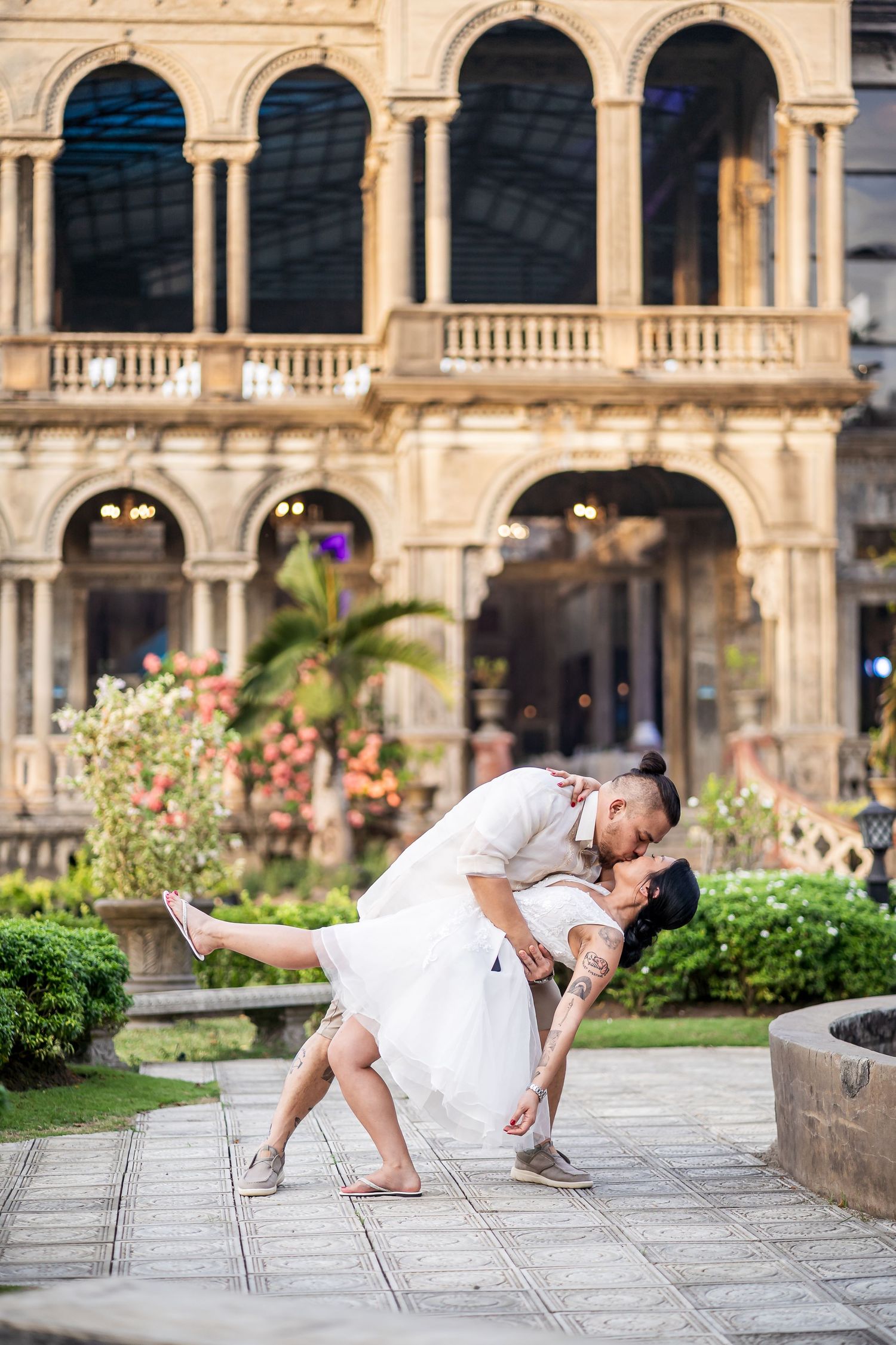 Romantic dance pose in front of historic Italian architecture with ornate arches.