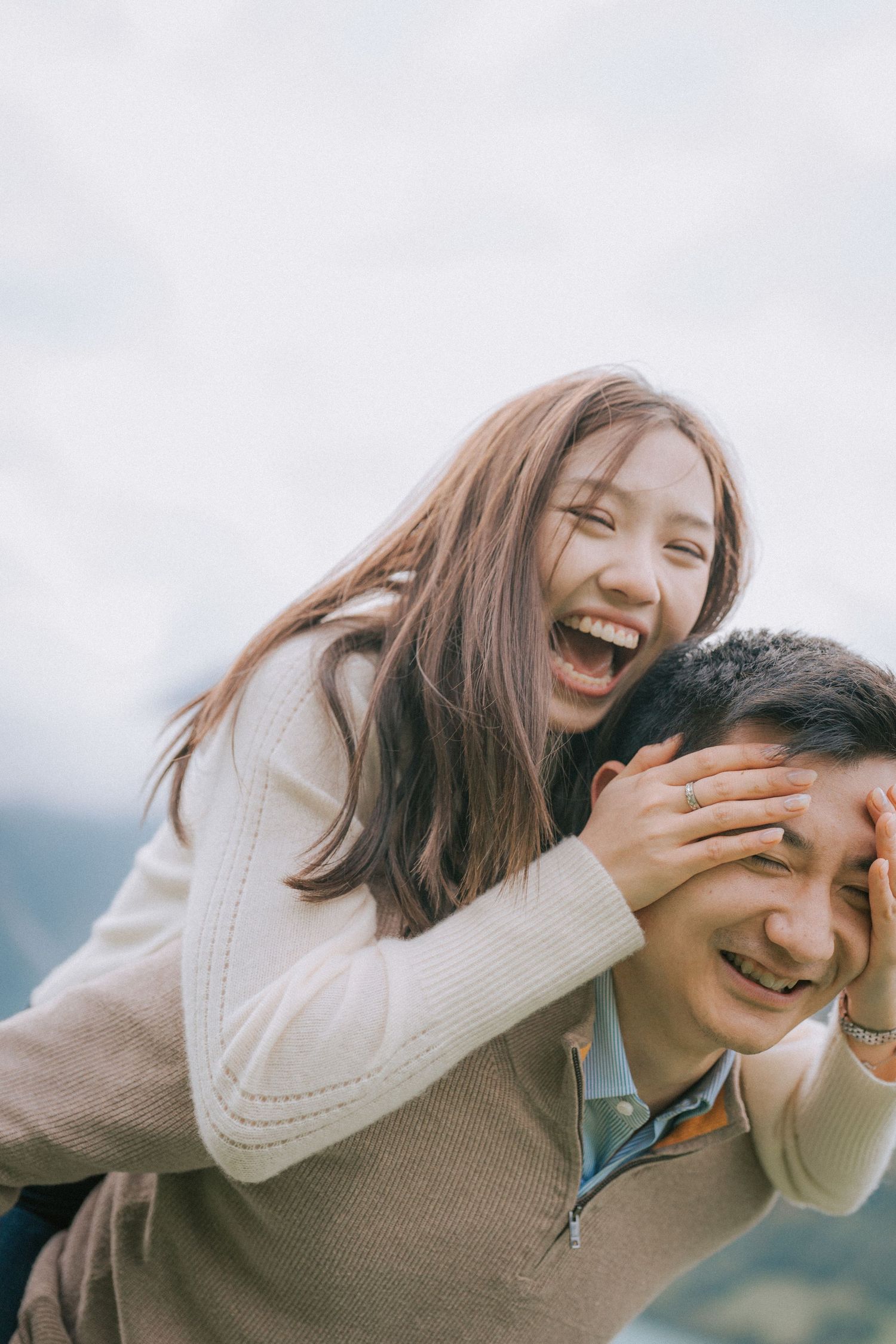 A joyful couple shares laughter and embraces while enjoying an outdoor moment together on a bright day.