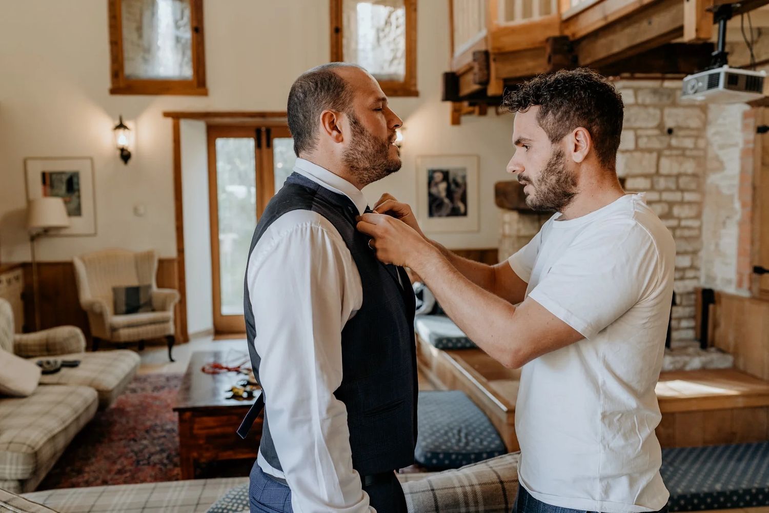 People embracing warmly in a casual indoor setting with natural lighting and wooden decor.