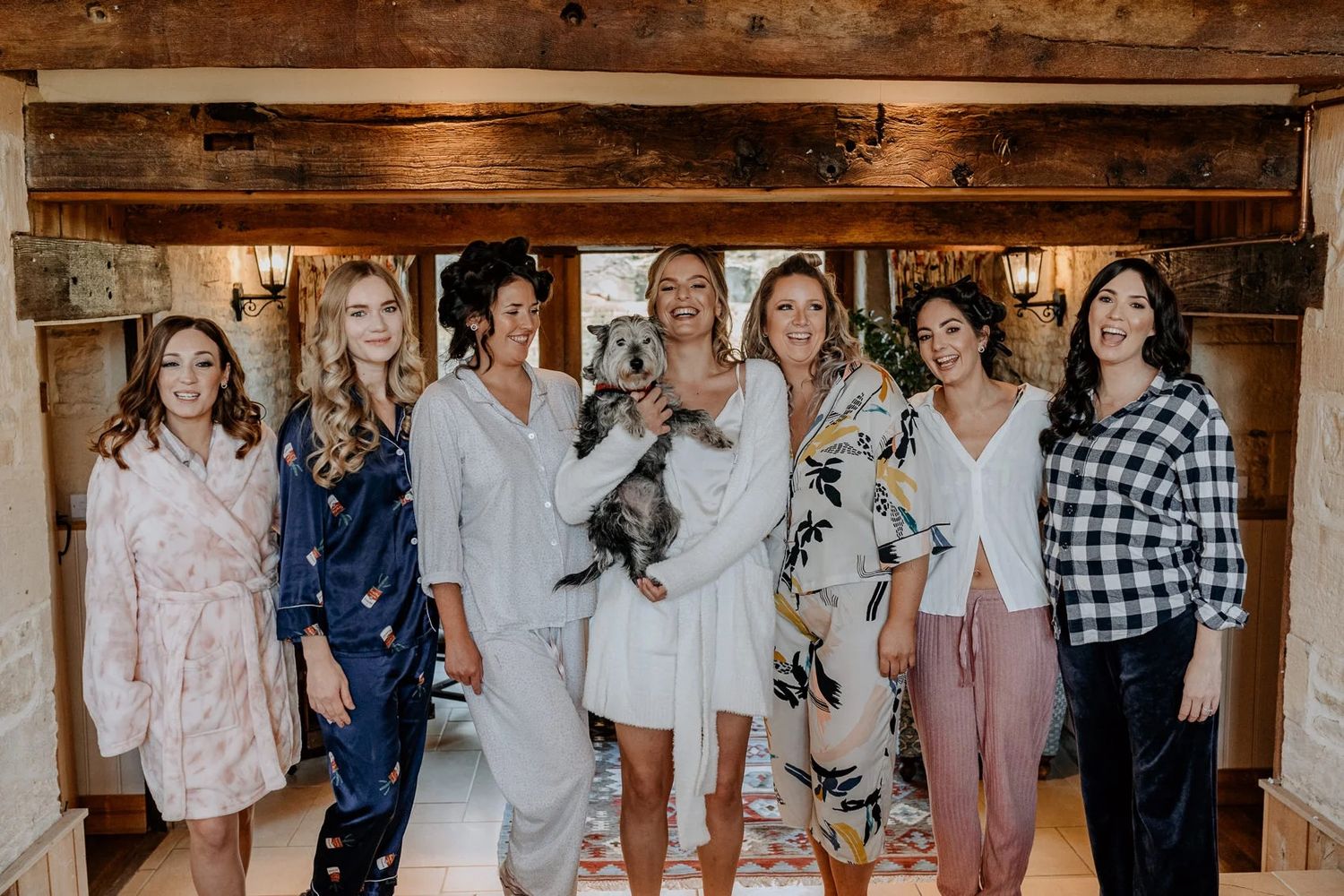 Group photo of wedding guests smiling together in front of rustic wooden wall.