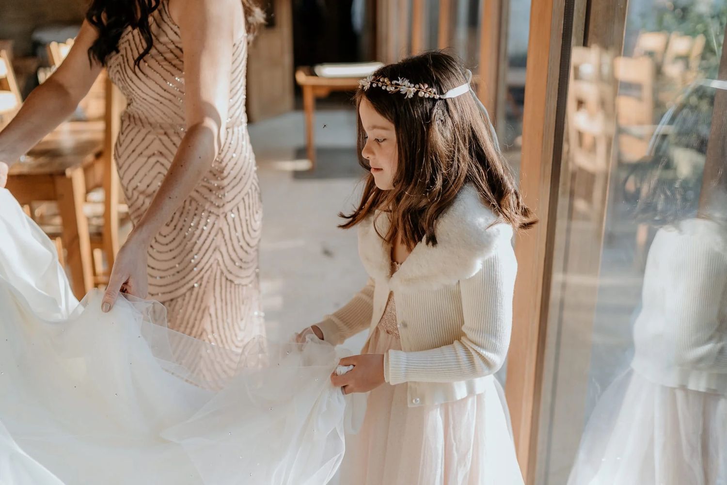 Wedding preparation scene with flowing white dresses in a bright interior space.