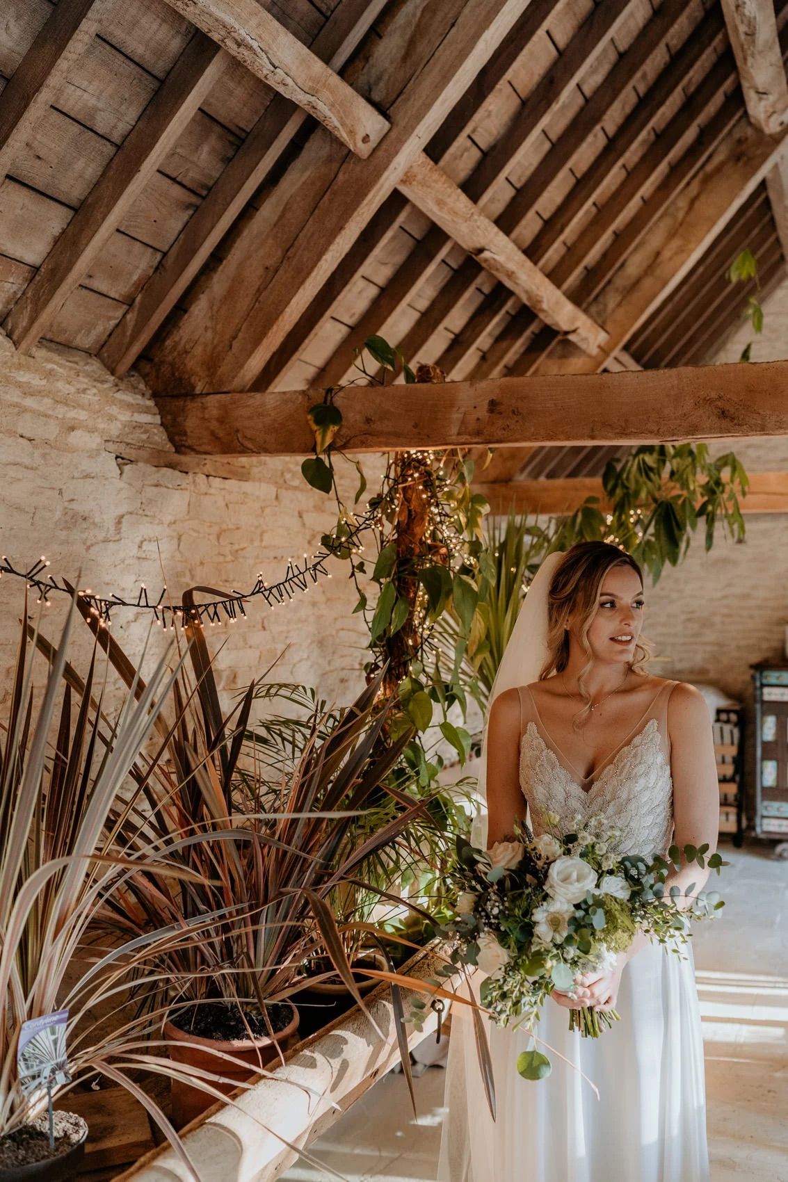 Rustic barn venue decorated with greenery and florals featuring exposed wooden ceiling beams.
