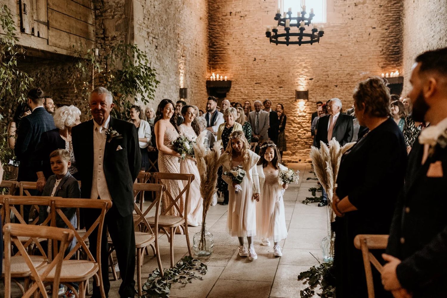 Wedding ceremony in progress inside a romantic stone barn with warm lighting.