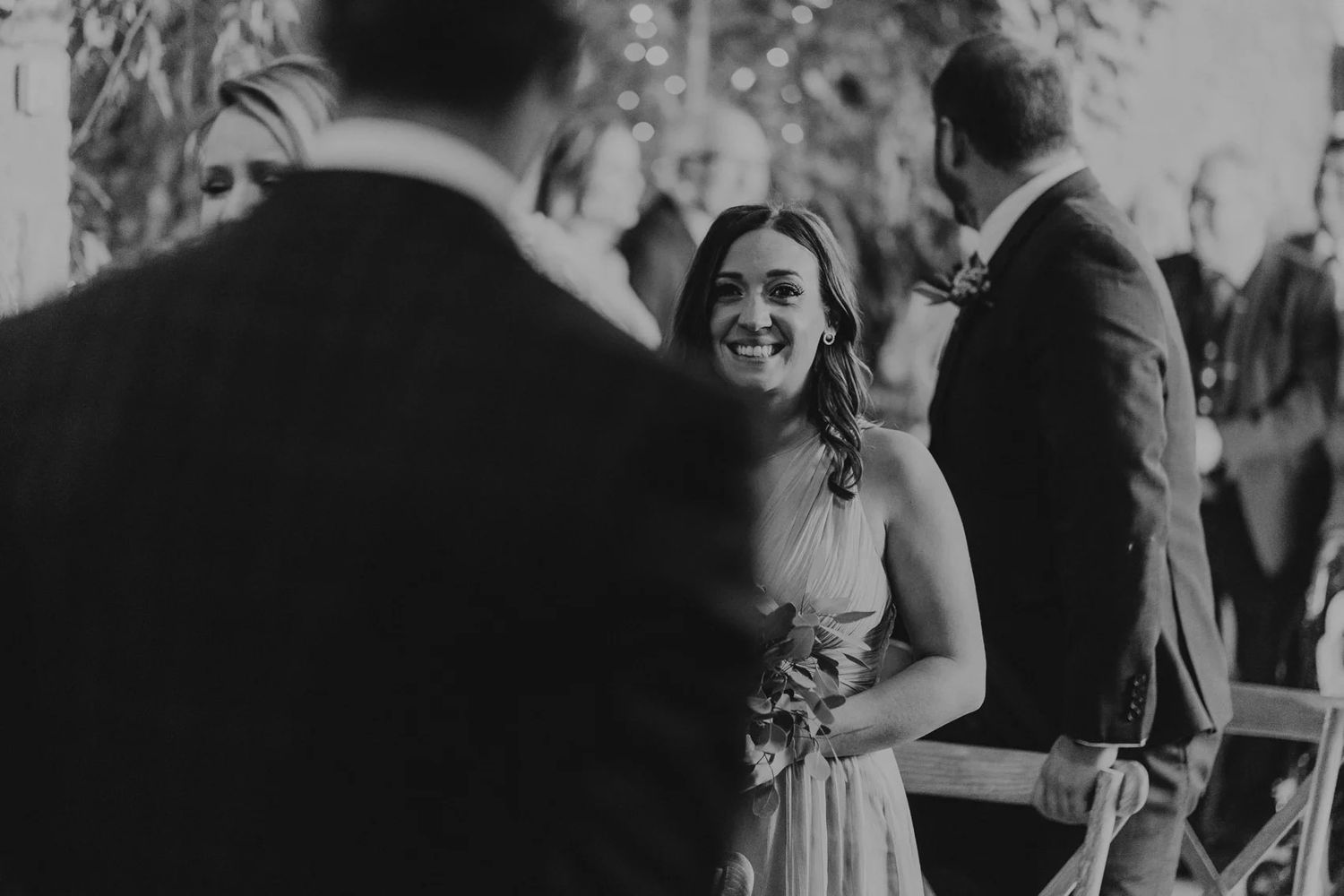 Wedding guests mingling and laughing during outdoor celebration in black and white.