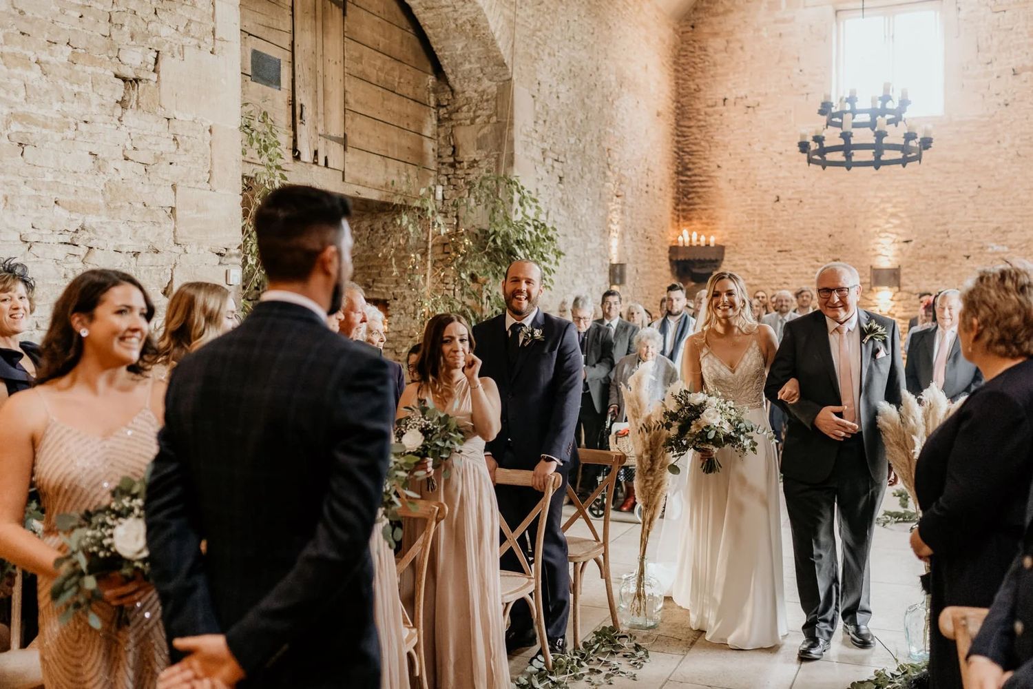 Wedding ceremony in progress inside a rustic stone-walled venue with guests watching.