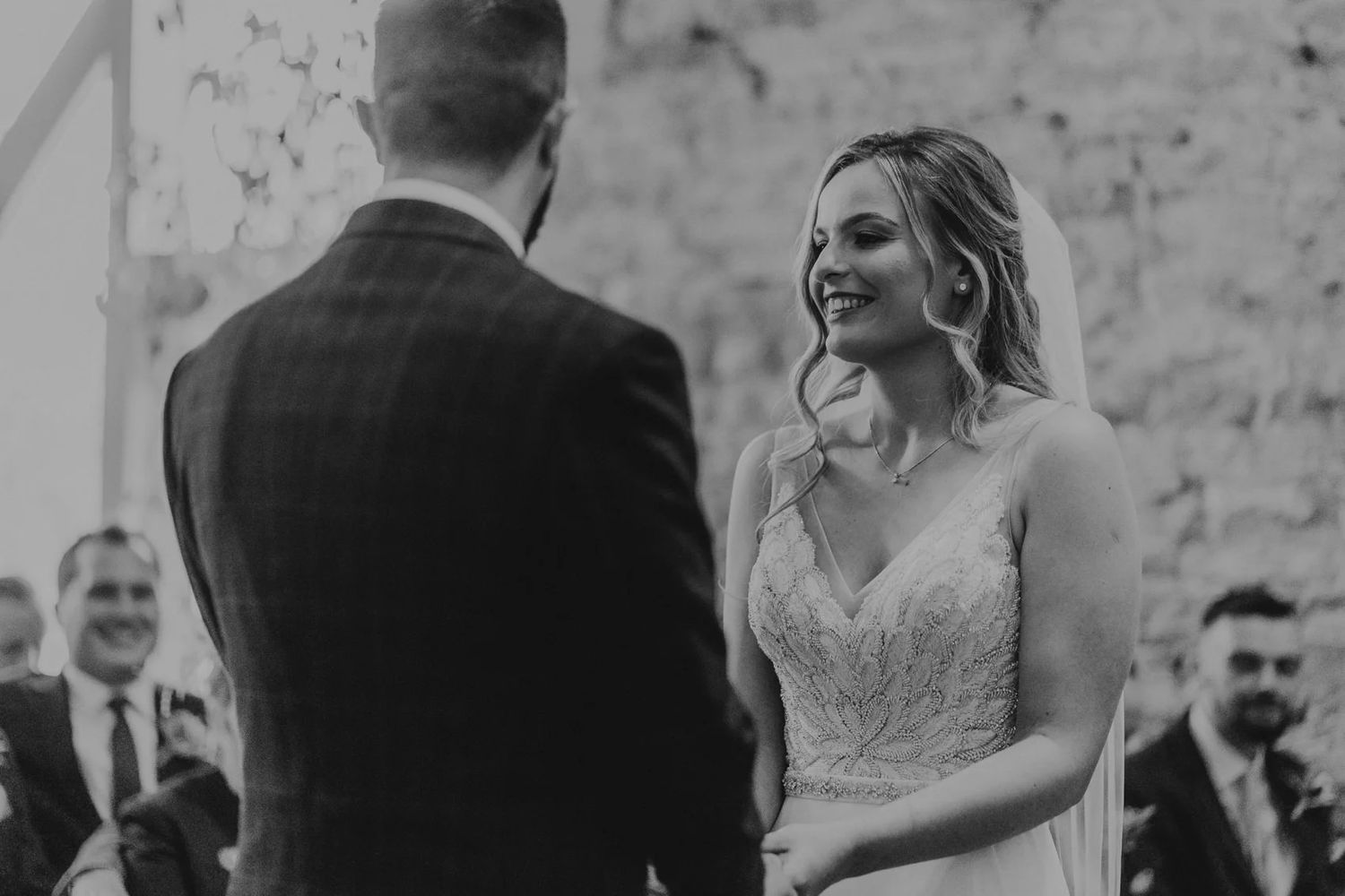 Black and white photo showing happy wedding guests laughing and gathering during an outdoor celebration.