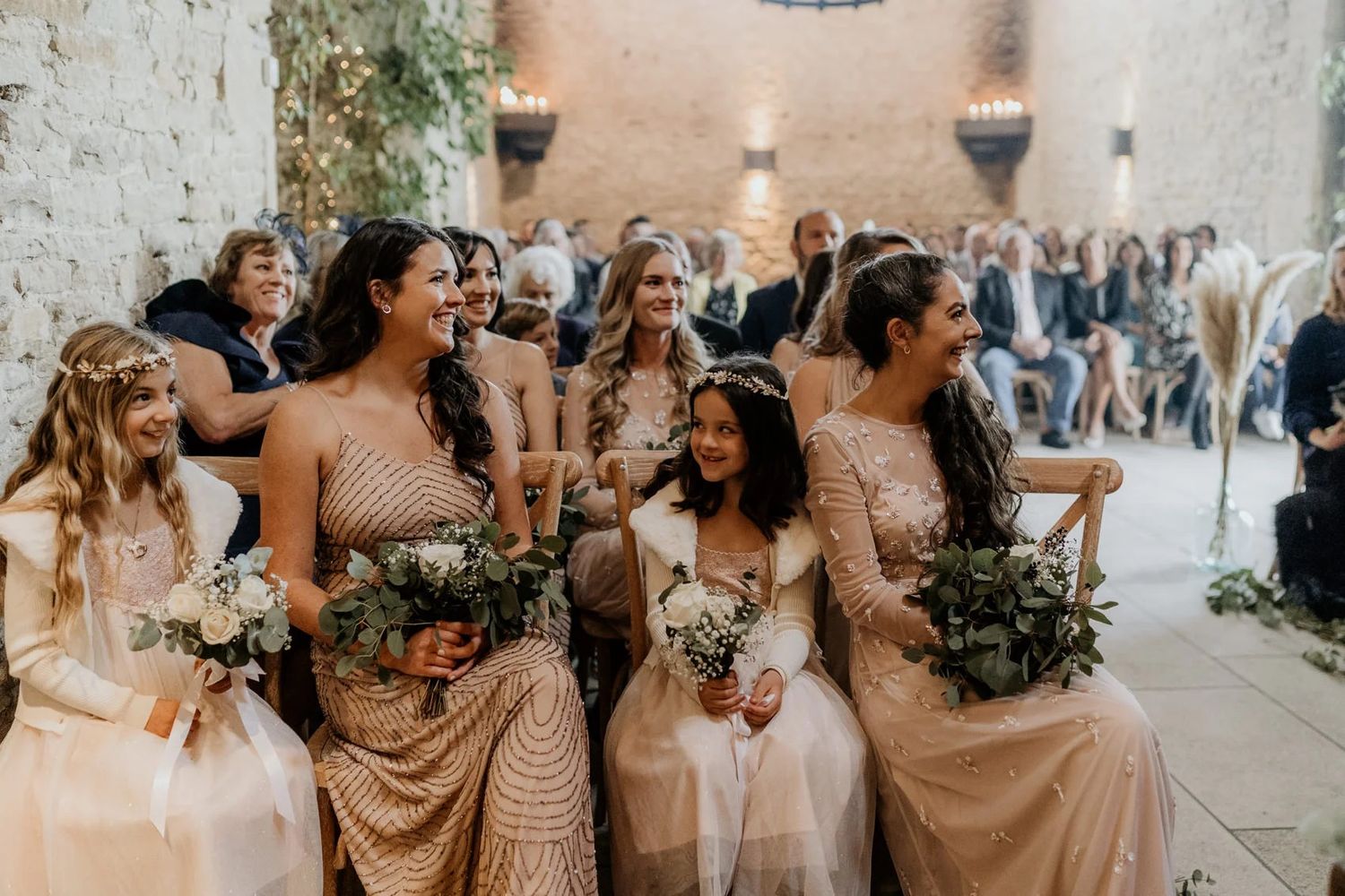 Wedding party posing together inside rustic stone venue with warm ambient lighting.