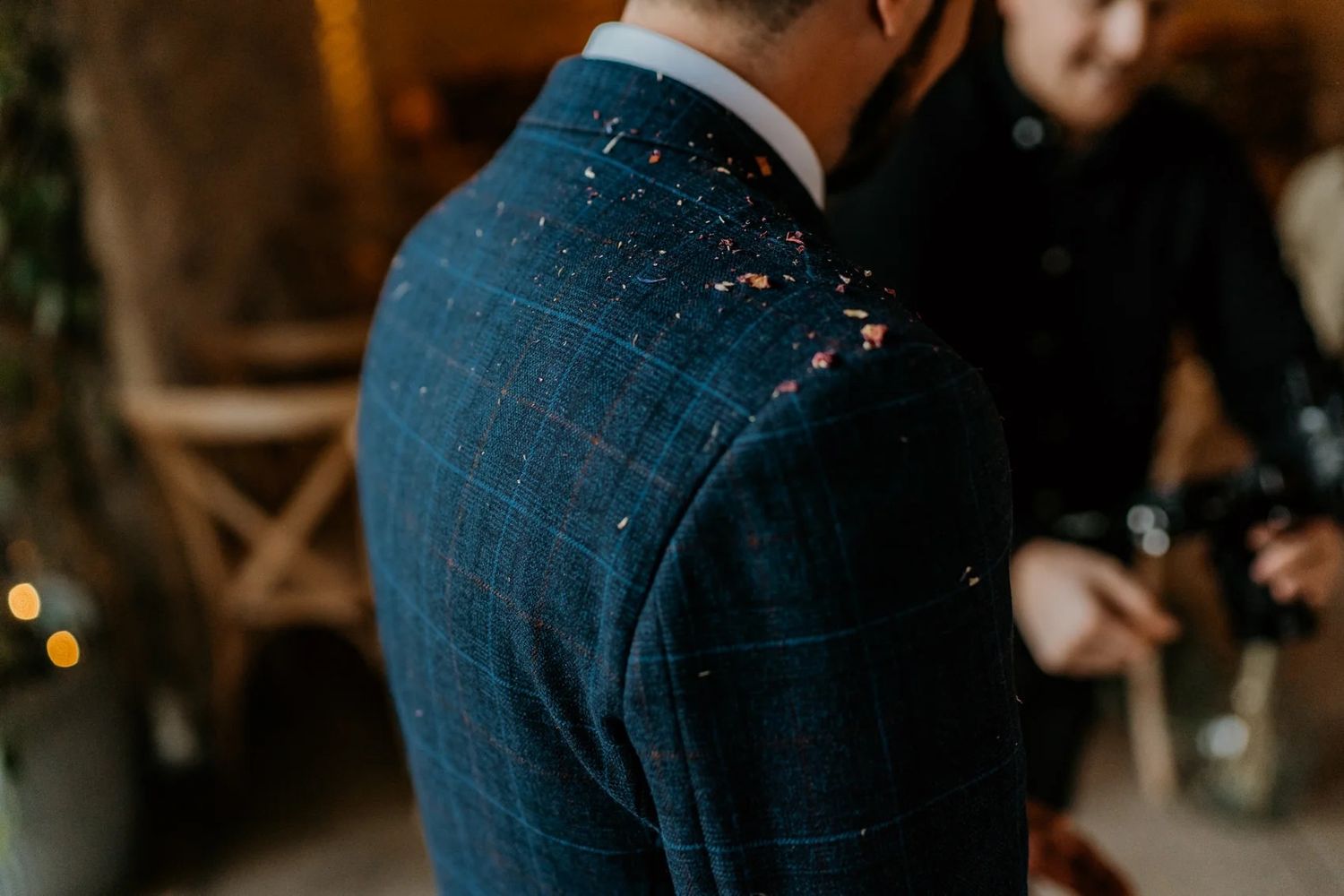 Close-up of formal attire and blue jeans in a dimly lit setting.