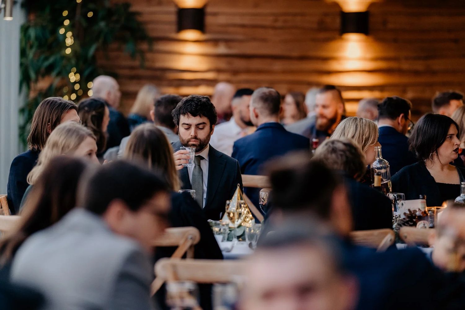 Rustic wedding reception venue with warm lighting and tables filled with celebrating guests.