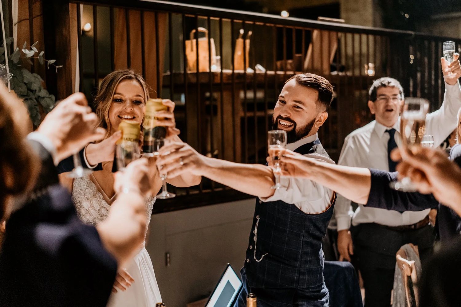 Wedding guests raise their hands in celebration during a joyful reception dance party.