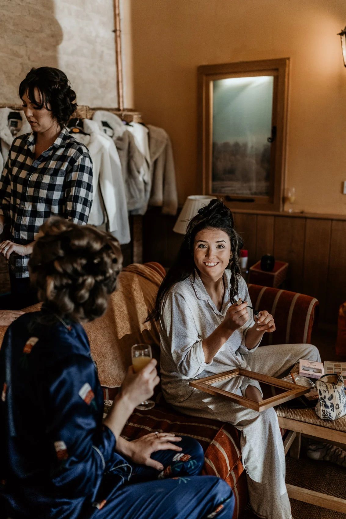 Bridal party members relaxing in cozy robes while getting ready in a warmly lit room.