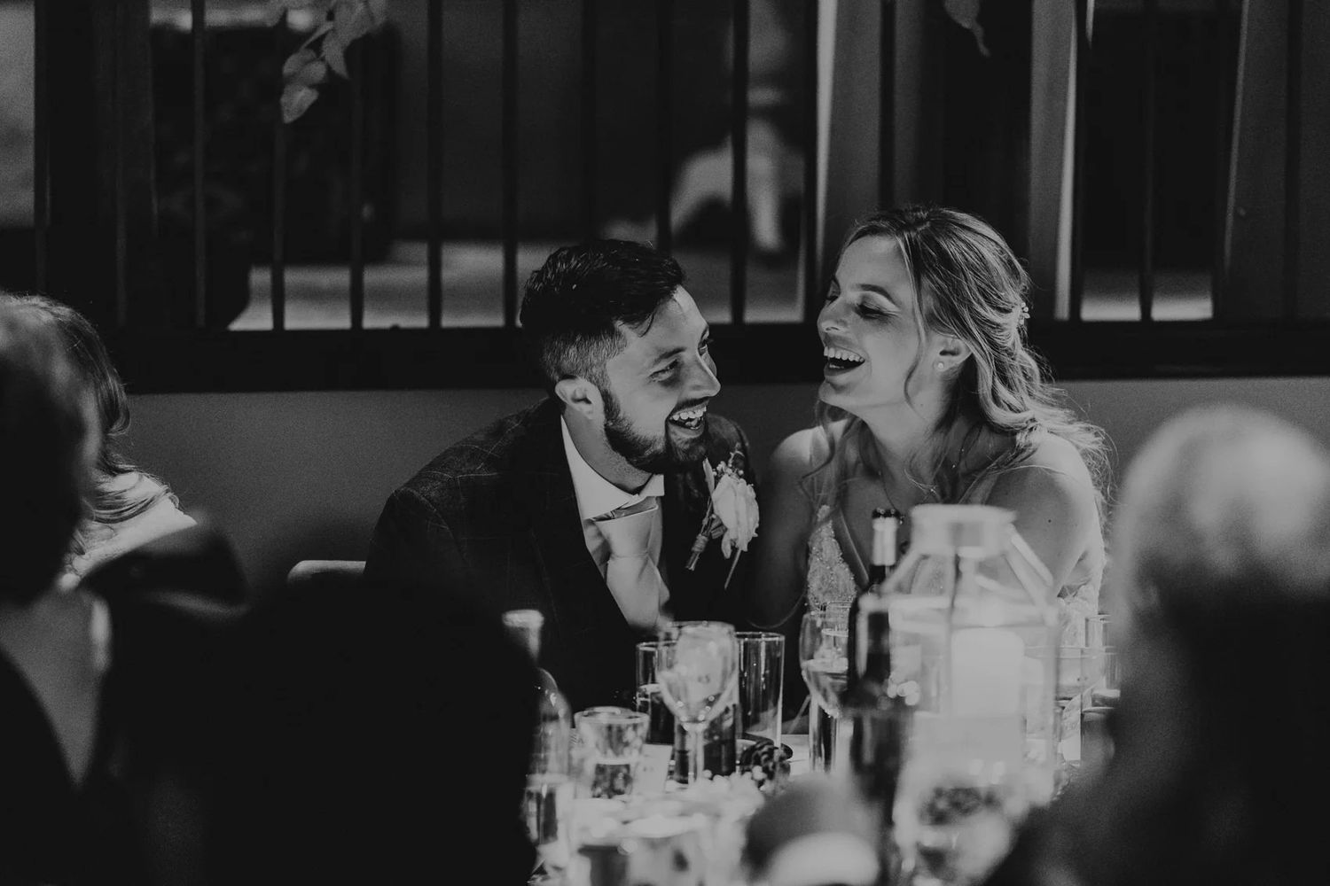 Black and white photo of wedding guests dancing and celebrating at an indoor reception.